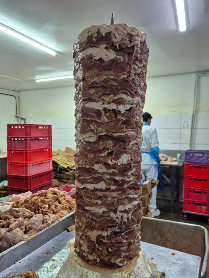 Üretim salonunda, üst kanat dilimleri kat kat dizilmiş çiğ hindi döner.